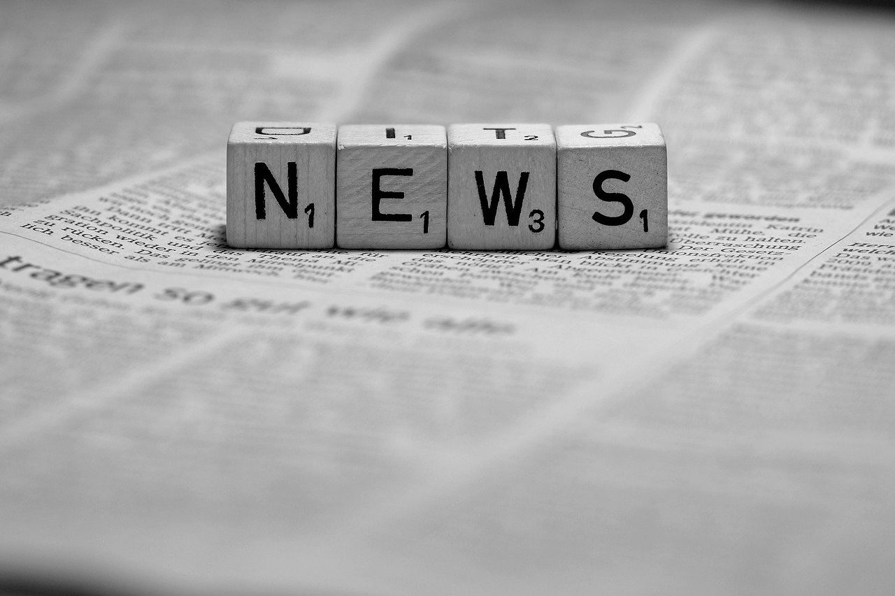 News Buchstabenwürfel bilden das Wort "NEWS" auf einer bedruckten Zeitung.