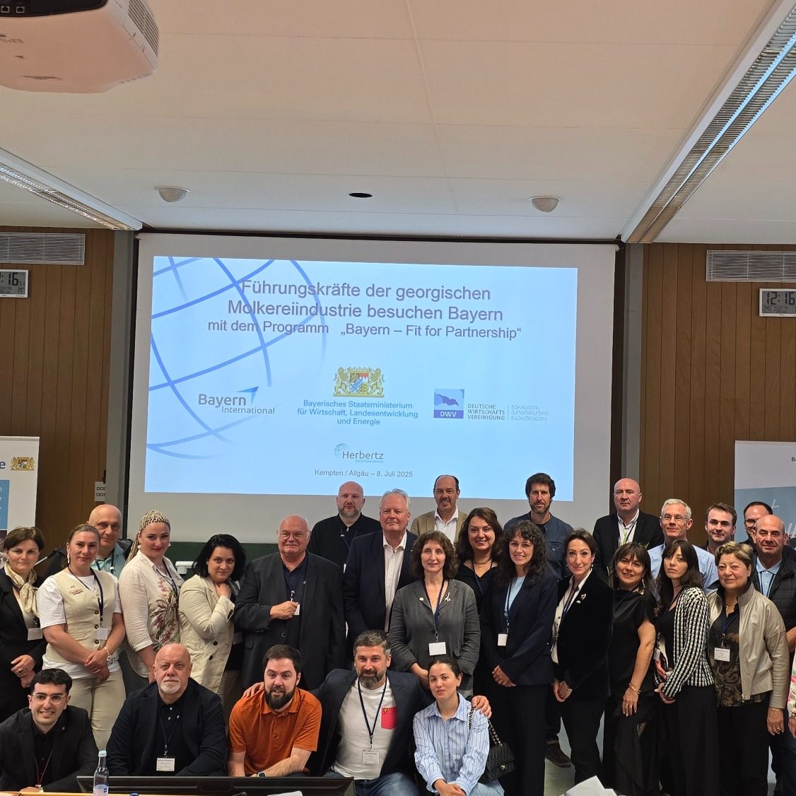 Georgien Gruppenbild Gruppenfoto von Teilnehmern einer Konferenz, mit Präsentation im Hintergrund.